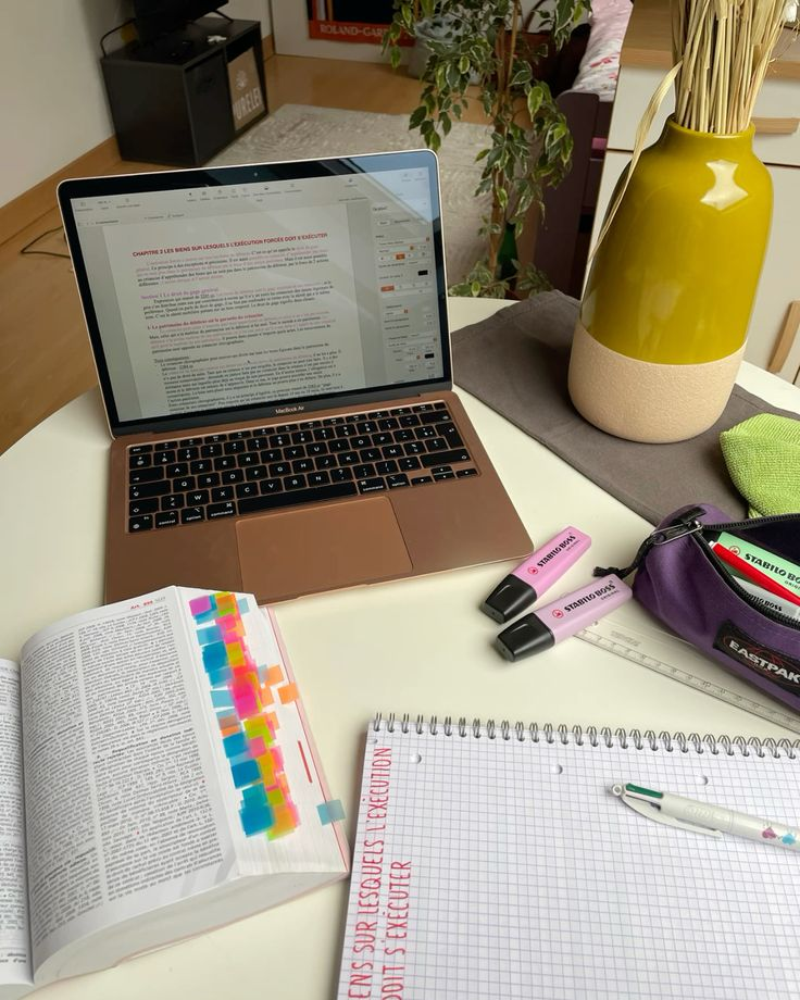Bureau d’étude avec ordinateur, livre annoté, cahier et surligneurs